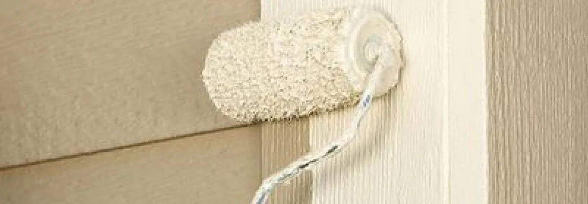 Person streicht Holzwand mit Farbrolle